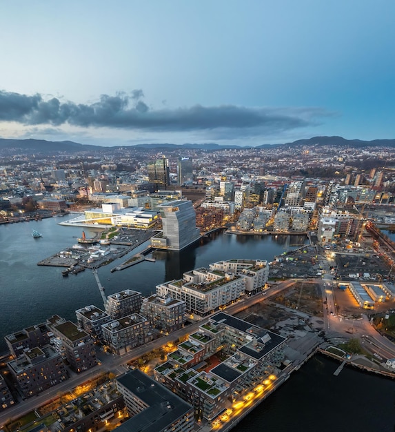 ノルウェーの海に囲まれた多くの建物とライトで,夕暮れのオスロの空中写真