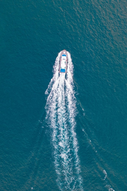 Аэрофотоснимок моря с пересекающей его моторной лодкой, оставляющей белый след