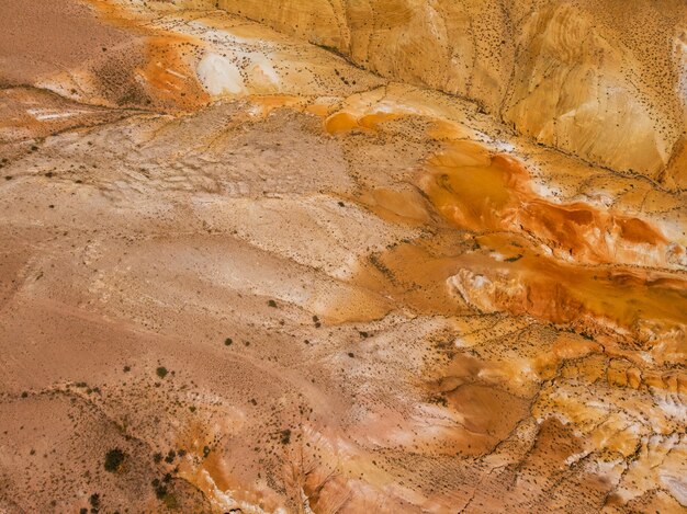 Aerial shot of the textured yellow nad red mountains resembling the surface of Mars