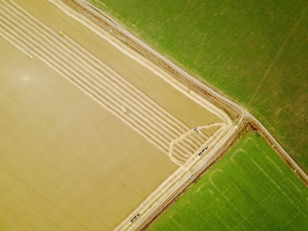 Aerial shot of yellow harvesters working on wheat field.