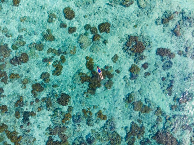 サンゴ礁の熱帯のカリブ海でシュノーケリングの人々を空中トップ