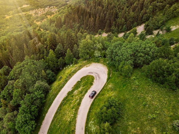 Aerial top down photo of a car driving on a beautiful snake serpentine road leading to mountain top in french Alps near Vaujany