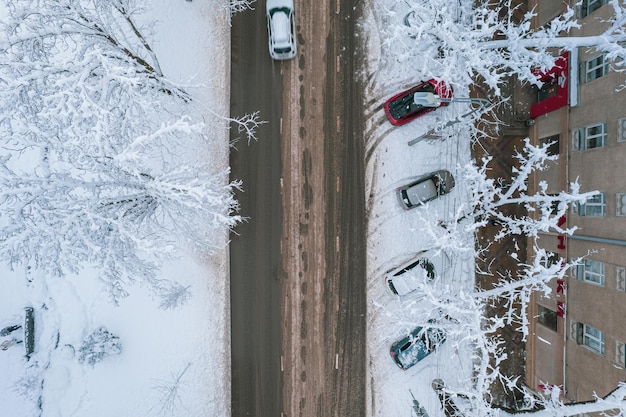 冬の雪に覆われた街のアスファルト道路の風景の空中トップダウン ビュー