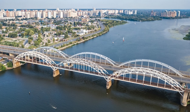 Aerial top view of automobile and railroad Darnitsky bridge across Dnieper river. Kiev city skyline, Ukraine