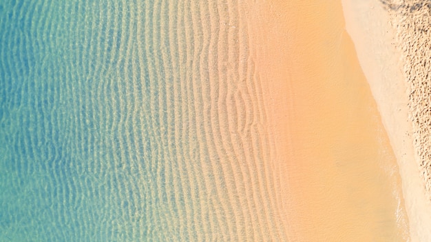 Aerial top view of Beach with shade emerald blue water and wave foam on tropical sea  background