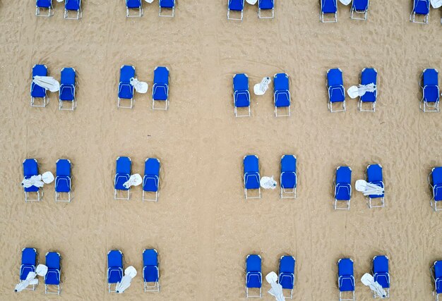 Aerial top view of a beach with white umbrellas and blue lounge chairs