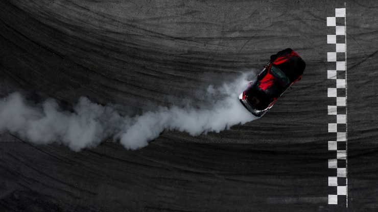 Photo aerial top view car drifting on race track with finish line and lots of smoke from burning tires.
