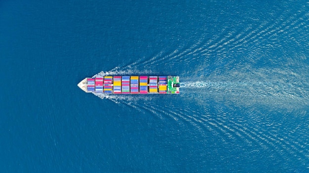 Aerial top view of cargo maritime ship with contrail in the\
ocean ship carrying container and running for export concept\
technology freight shipping sea freight by express ship