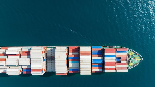 Aerial top view of cargo ship carrying container and running for export goods from cargo yard port to custom ocean concept technology transportation customs clearance