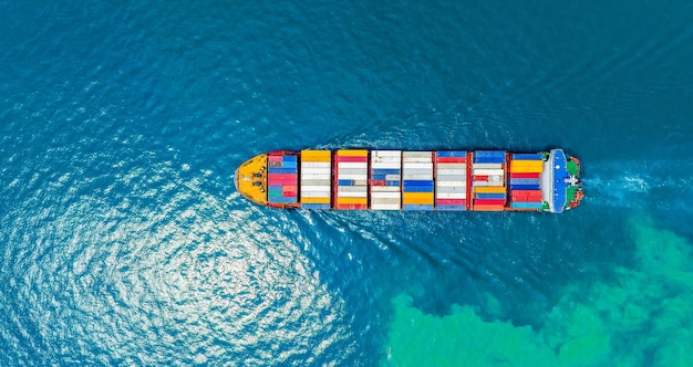 Aerial top view of cargo ship carrying container and running for export goods from cargo yard port to custom ocean concept technology transportation customs clearance