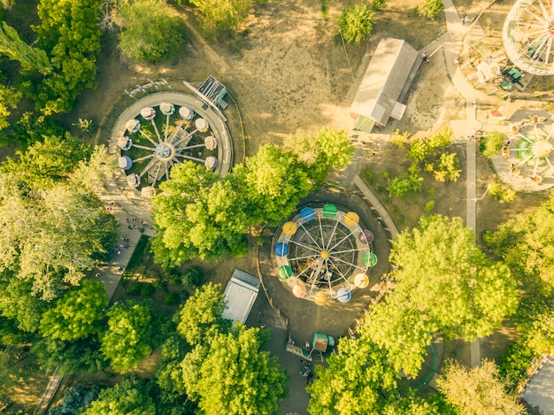 aerial top view of city park caorusel with happy children on summer holidays.