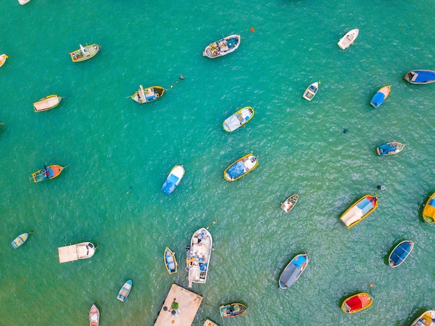 Aerial top view of colorful boats in the green water