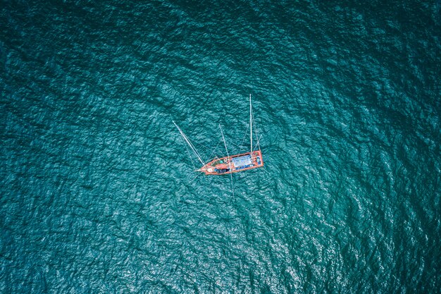 Aerial top view fishing boat on the green sea