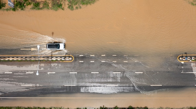 Aerial top view of flooded the village and country road with\
car, view from above shot by drone