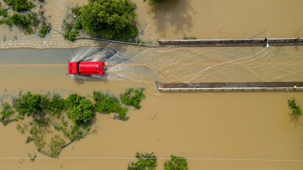 空中のトップビューの浸水村と田舎道、赤い車、上からの眺めはドローンで撮影