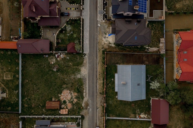 Aerial top view of a house with paved yard with green grass lawn with concrete foundation floor.