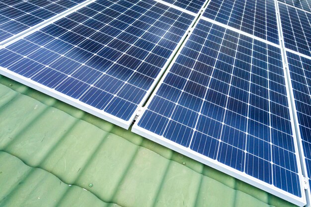 Aerial top view of new modern residential house cottage with blue shiny solar photo voltaic panels system on roof. Renewable ecological green energy production concept.