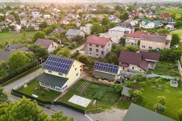 Aerial top view of new modern residential house cottage with blue shiny solar photo voltaic panels system on roof. Renewable ecological green energy production concept.