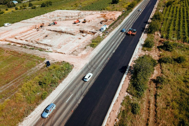 Aerial top view of roadworks with road workers lay asphalt work on laying of asphalt aerial photogra...