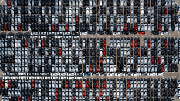 Aerial top view rows of new cars parked in distribution center on car factory Automobile and automotive car parking lot for commercial business industry to dealership for sale