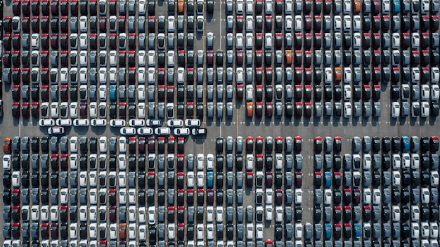 Aerial top view rows of new cars parked in distribution center\
on car factory automobile and automotive car parking lot for\
commercial business industry to dealership for sale