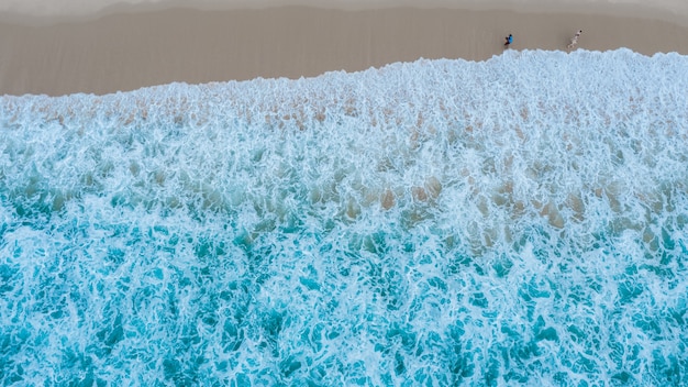 Aerial top view of sandy beach with traveling tourists in beautiful the sea wave