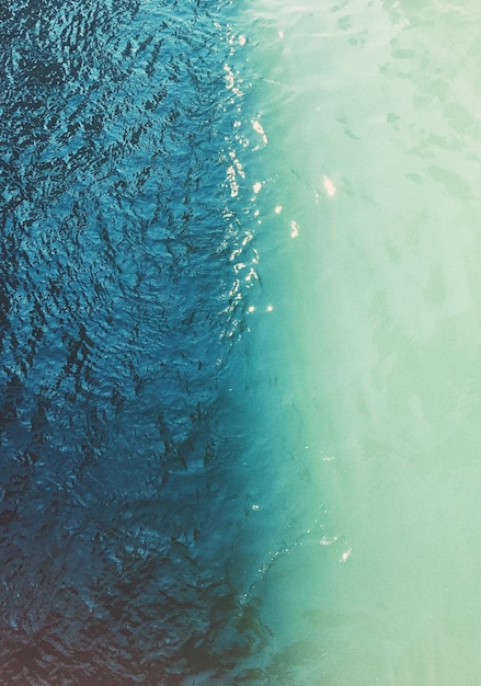 Aerial top view of waving shiny seawater in two different colors