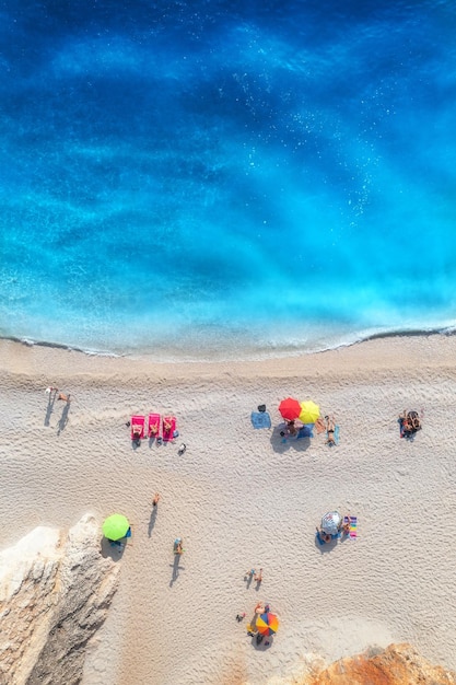 Aerial view of adriatic sea waves sandy beach and umbrellas with lying people at sunset in summer Tropical landscape with clear turquoise water Top view from drone Lefkada island Greece Travel