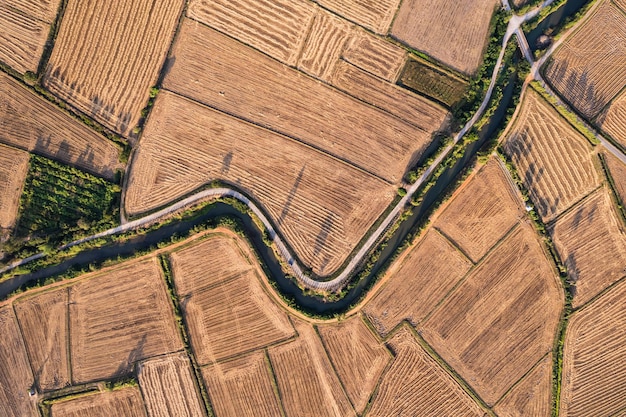 Aerial view of agricultural barren fields with irrigation canal in farmland at countryside
