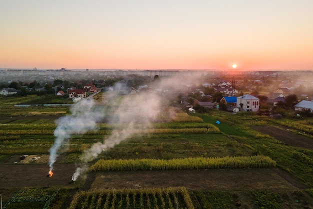 Aerial view of agricultural waste bonfires from dry grass and straw stubble burning with thick smoke polluting air during dry season on farmlands causing global warming and carcinogen fumes