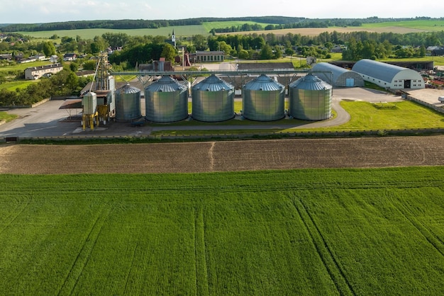 Aerial view on agro silos granary elevator on agroprocessing\
manufacturing plant for processing drying cleaning and storage of\
agricultural products flour cereals and grain