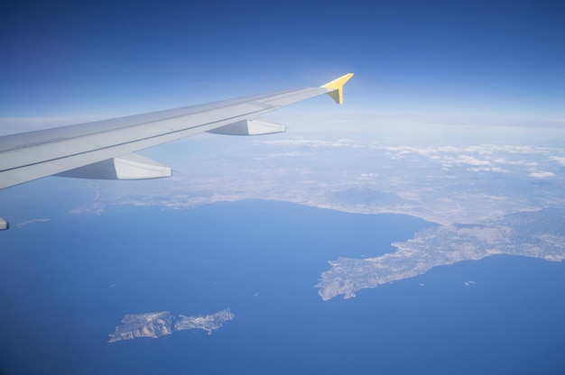 Aerial view of airplane flying over landscape against sky