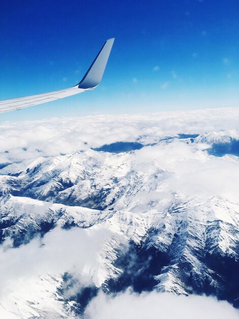 Aerial view of airplane flying over snow against sky