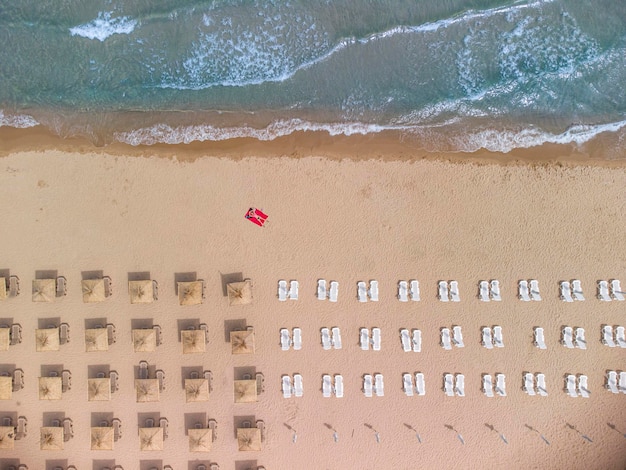 Aerial view of an amazing empty sand beach with straw beach umbrellas and turquoise clear water