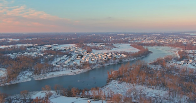 Aerial view of amazing winter sunset in suburb city with snow covered of residential quarters by the