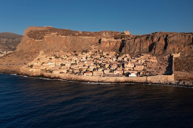 日の出ギリシャの島の海岸の要塞の壁の後ろに古代都市モネンバシアの航空写真