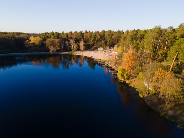 Aerial view of the autumn forest near the river in the afternoon