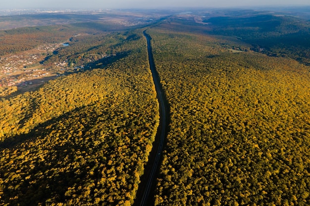 Aerial view of autumn woods and the highway that crosses the forest k images at sunset with a dramat...