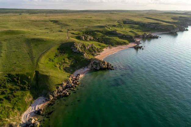 Foto veduta aerea della spiaggia grandi colline intorno giornata di sole all'alba mare verdastro drone photo