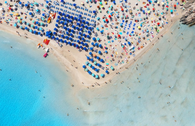 Aerial view of beautiful beach with white sand colorful umbrellas swimming people in blue sea at summer sunny day la pelosa beach sardinia italy top drone view of sandy beach transparent water