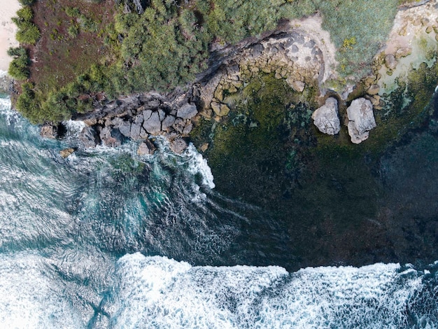 Vista aerea delle belle onde del mare blu che si infrangono sulla costa sabbiosa