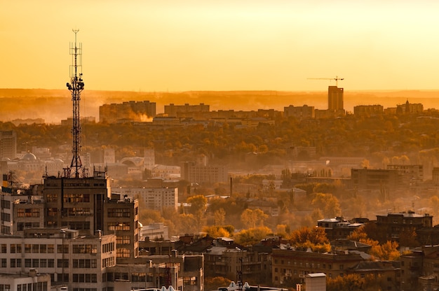 вид с воздуха на красивые горящие огни вечернего города, окутанного туманом, со зданиями