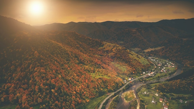 写真 川沿いに位置する美しい峡谷の村の空撮劇的な秋の山の風景と