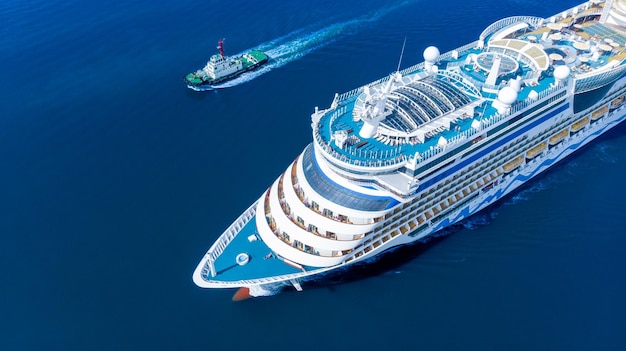 Aerial view of beautiful white cruise ship above luxury cruise running with tug boat in the ocean sea concept tourism travel on holiday take a vacation time on summer