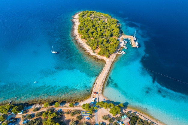 Aerial view of beutiful small island in sea bay at sunrise in summer in Murter Croatia Top view of transparent blue water green trees mountain sandy beach boats and yachts Tropical landscape