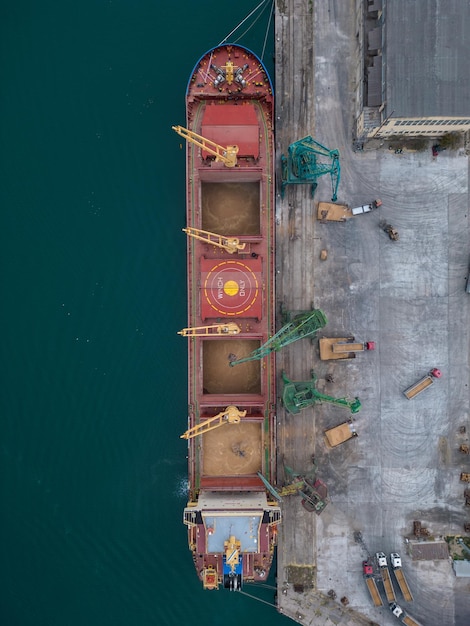 Aerial view of big cargo ship bulk carrier is loaded with grain\
of wheat in port