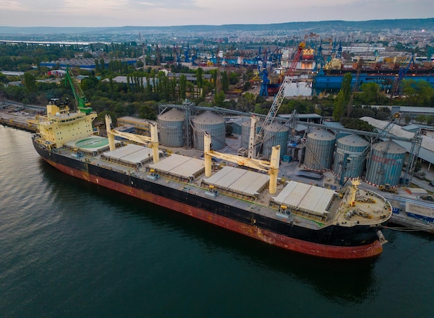 Aerial view of big cargo ship bulk carrier in the port at sunset aerial view from flying drone