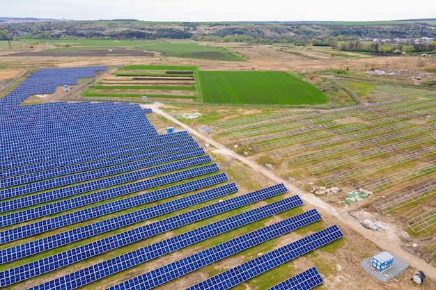 Photo aerial view of big electric power plant construction with many rows of solar panels on metal frame for producing clean ecological electrical energy. development of renewable electricity sources.