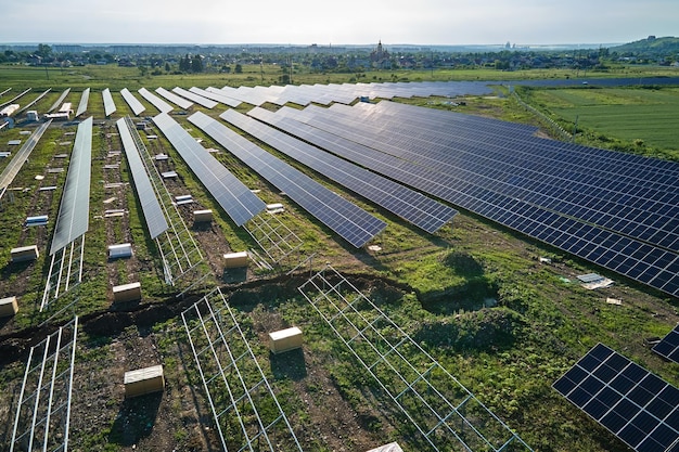 Aerial view of big electric power plant under construction with\
many rows of solar panels on metal frame for producing clean\
electrical energy development of renewable electricity sources
