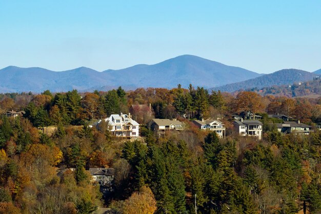 Aerial view of big family houses on mountain top between yellow trees in North Carolina suburban area in fall season Real estate development in american suburbs